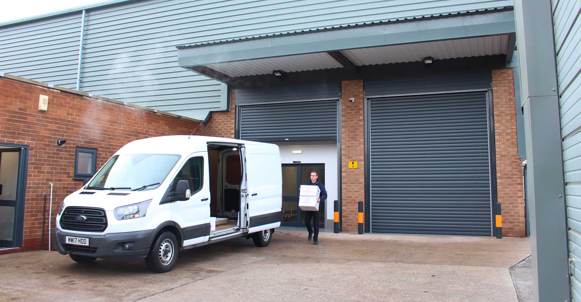 man in black jacket transporting 2 boxes at the same to a small white truck