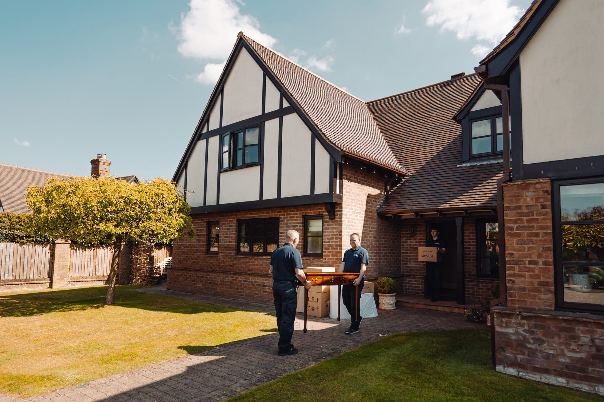 two men carrying a table from the house